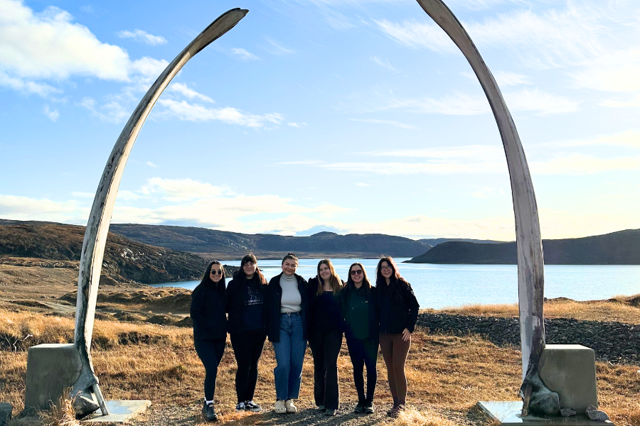 ICE alumni, six people standing beneath a whale bone arch in Niaqunngut (Apex), near Iqaluit.