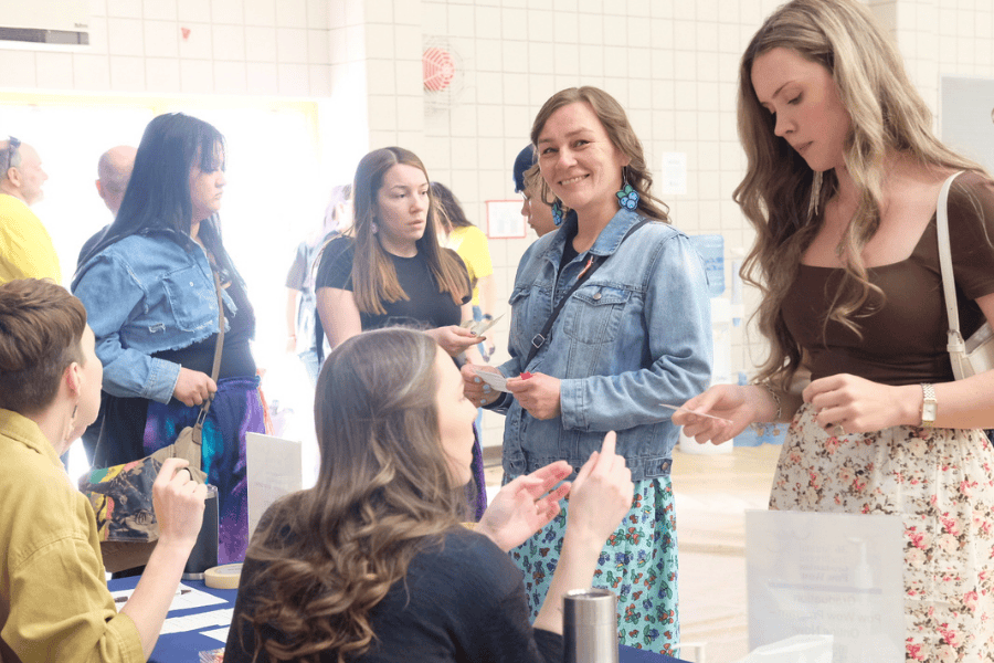 Group of people chatting and registering at an indoor event table.