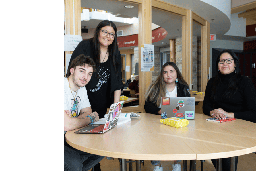 Four students gathered around a table in a campus study space.