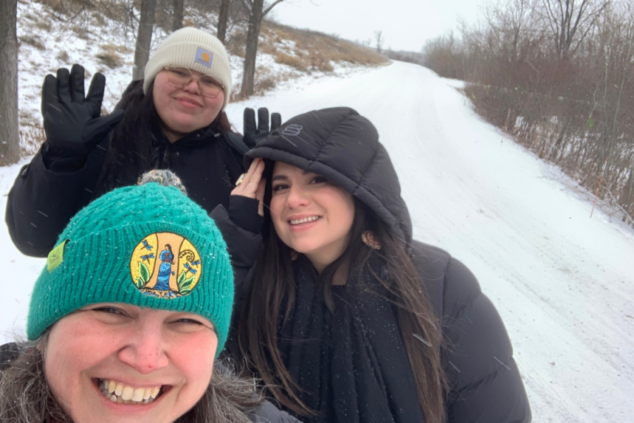 Three people smiling during a winter walk on a snow-covered trail.