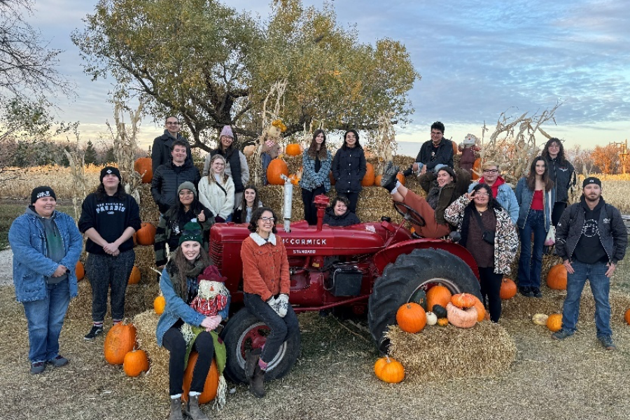 Neechiwaken participants pose with pumpkins and a tractor.