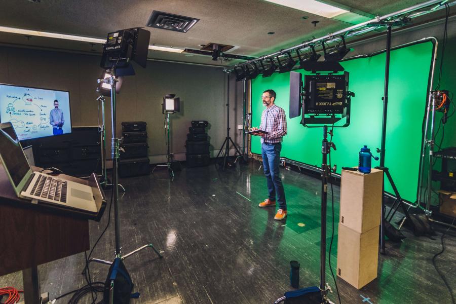 Man standing in front green screen on production set.