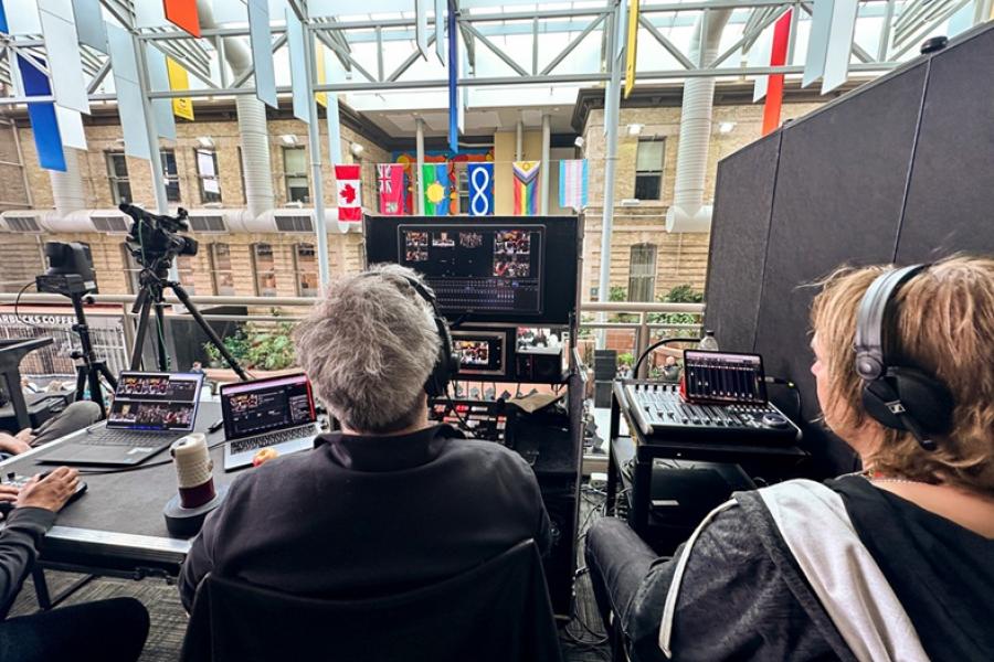 video and audio board with operators sitting at it watching convocation
