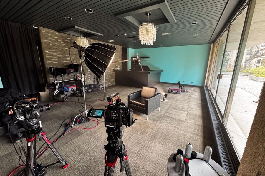 Video and cameras and lights set up to record in a room pointing at a chair