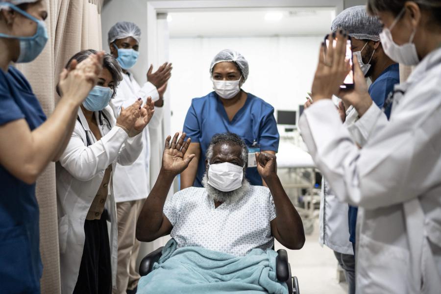 Patient celebrating recovery with doctors surrounding him.