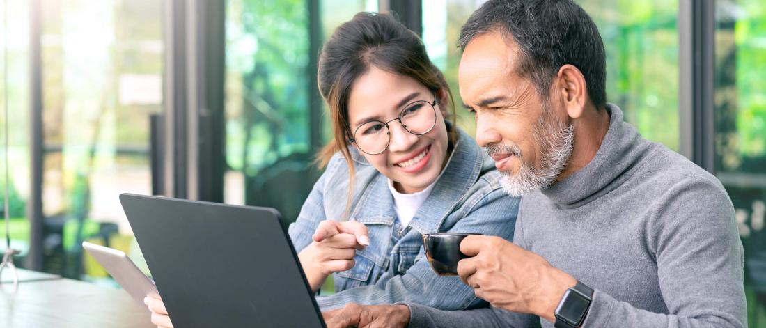 Couple looking at an open laptop together.