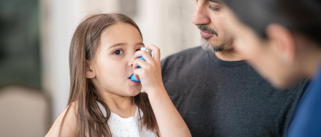 Little girl learning to use an asthma inhaler.