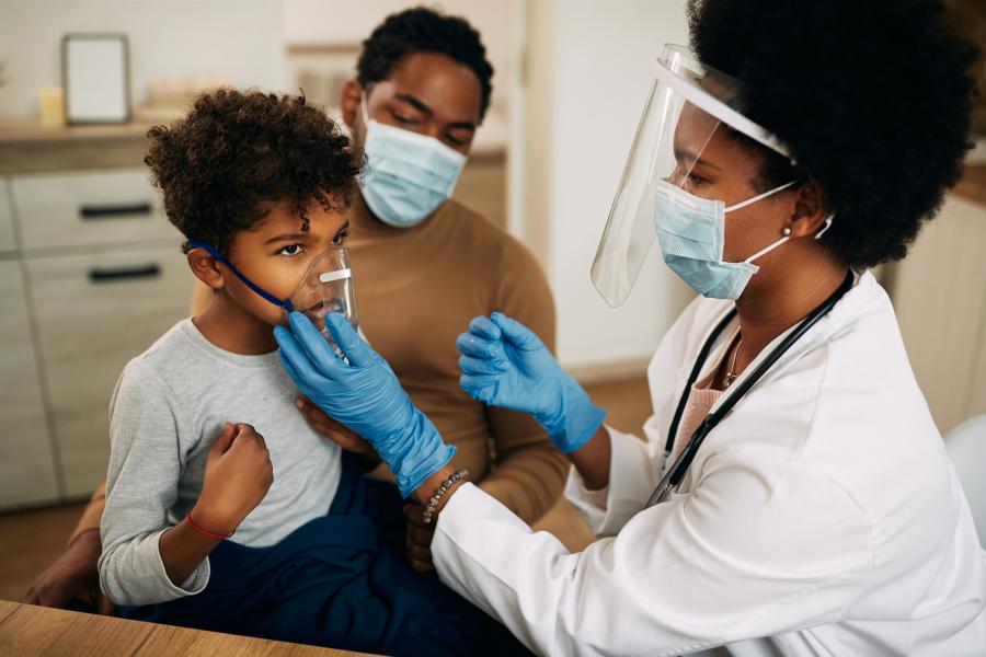 Physician examines a child wearing a nebulizer.
