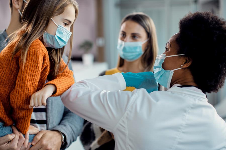 A doctor gives an elbow-bump to a child.