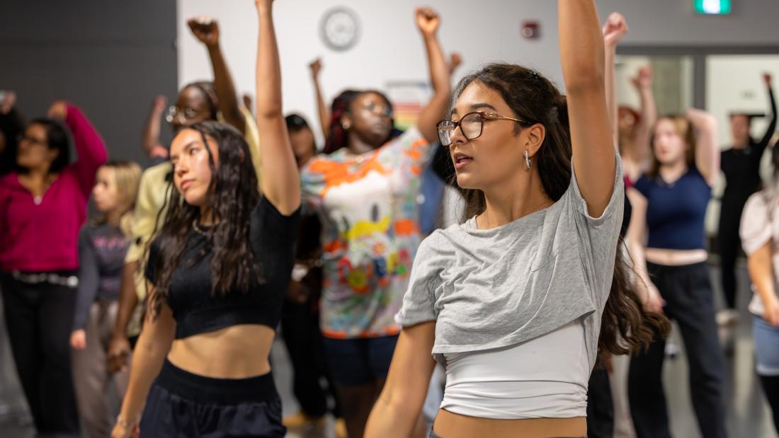 Two women holding their hands up during a kpop dance class