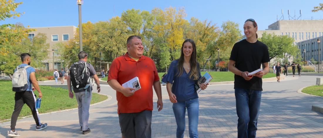 Three people walking together along Curry Place at the University of Manitoba Fort Garry campus. 