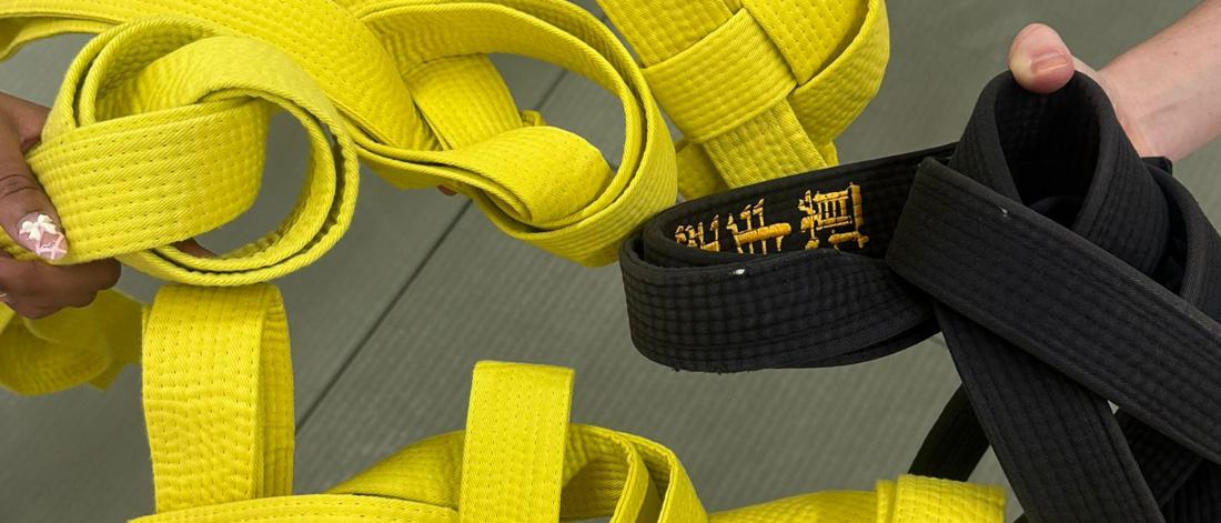 A group of hands holding martial arts belts