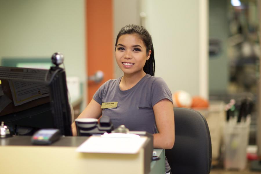 An FKRM student stands at a desk in front of a work station. 