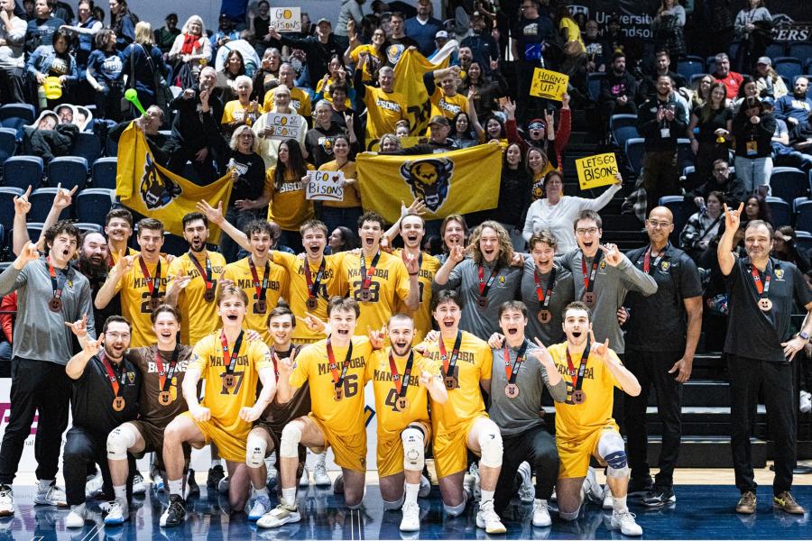 The bisons men's volleyball team celebrating their U Sports bronze medal infront of a crowd
