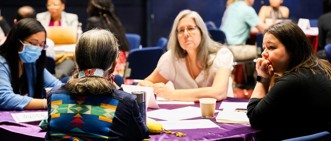 People at a SPECTRUM workshop sitting around a table listening intently to Knowledge Keeper Leslie Spillett Elder