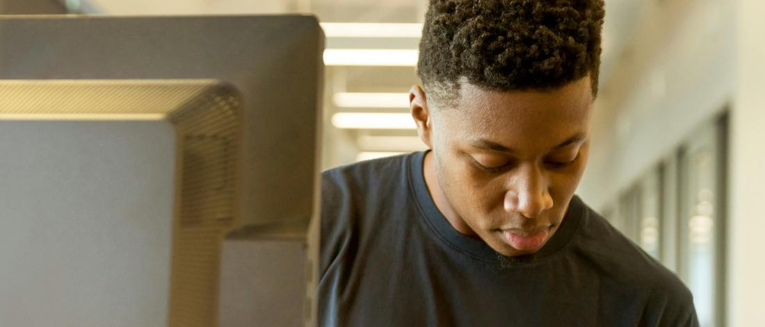 A man with short black hair works in front of computer