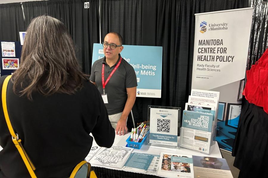 MCHP staff engage passer's by at a booth set up in a conference hall 