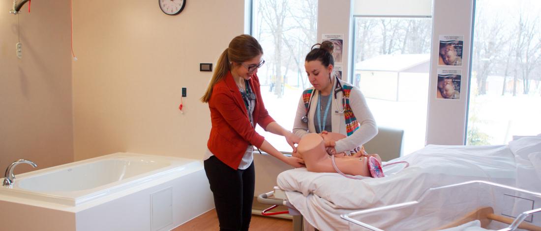 A student practices the birthing process using a simulation mannequin.