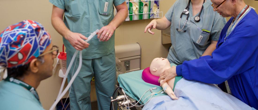 Doctors and students work with a medical mannequin during an anesthesia simulation.