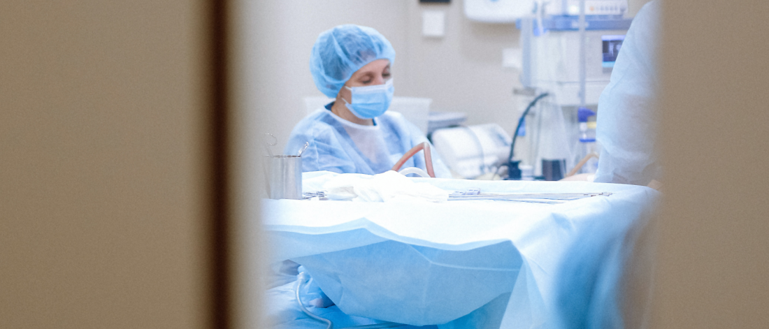 a surgeon is observed with a patient from outside the operating room.