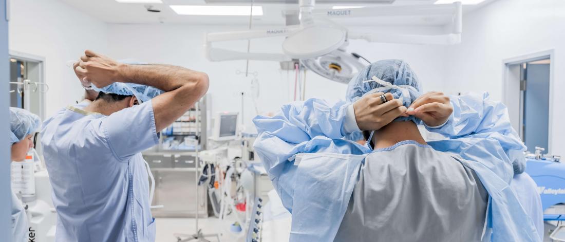 Surgeons tying on masks.