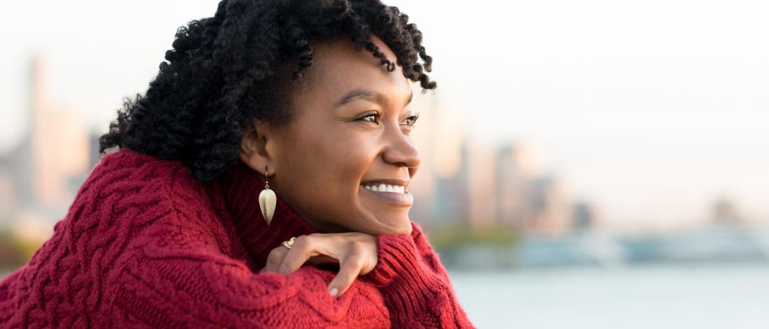 Woman looking throughtful sitting by the water.