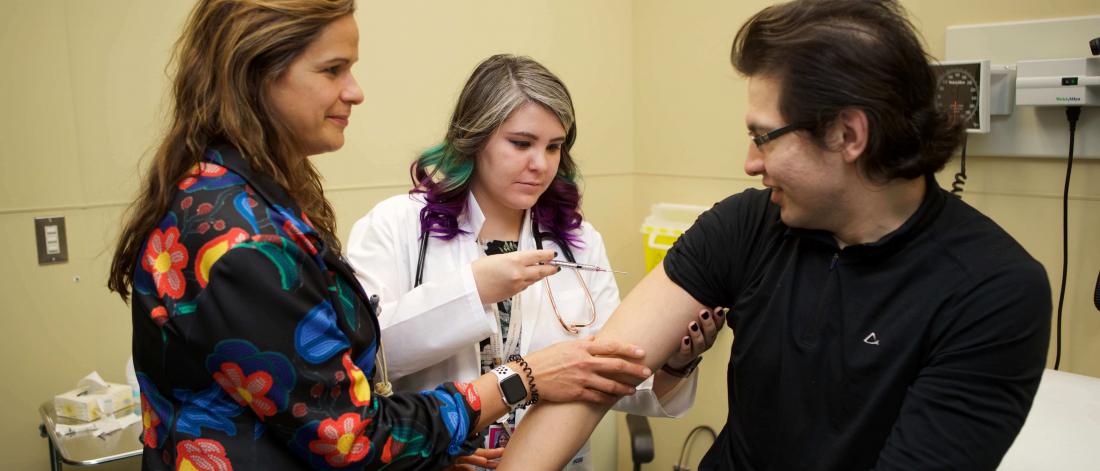 Intern gives an injection to a patient under supervision of a doctor.