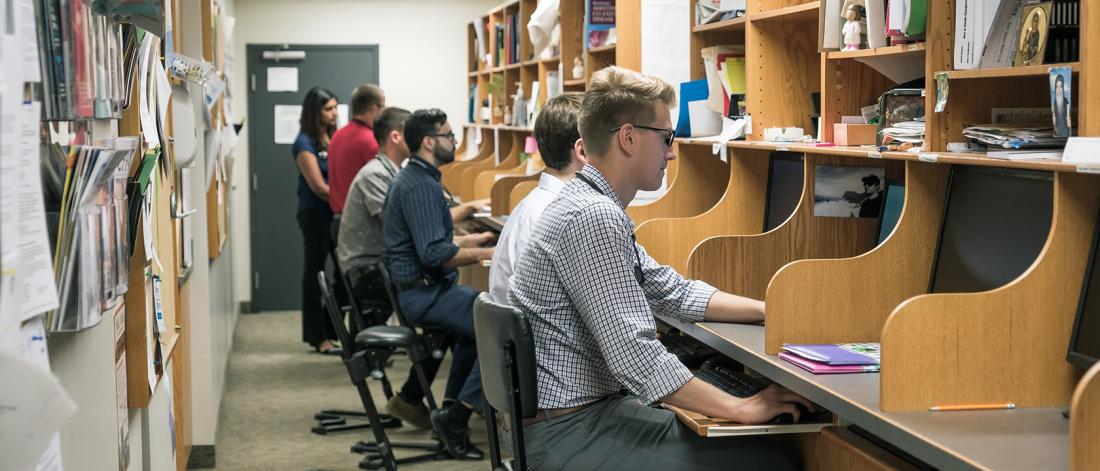 A row of students at study carrels.