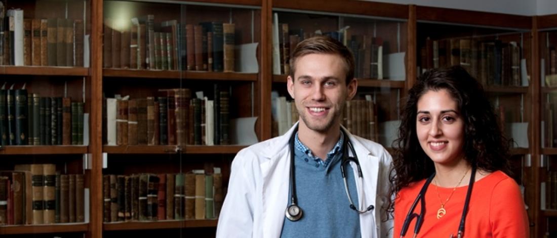 two people posing in a library, smiling at the camera.