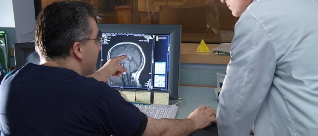 Two people reviewing a brain scan on a monitor.