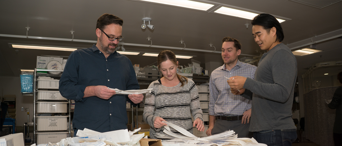 A group of physicians review a pile of paperwork. 