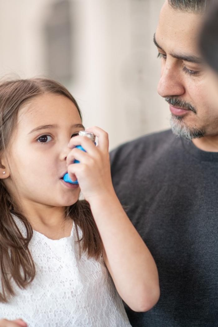 Little girl uses an asthma inhaler.