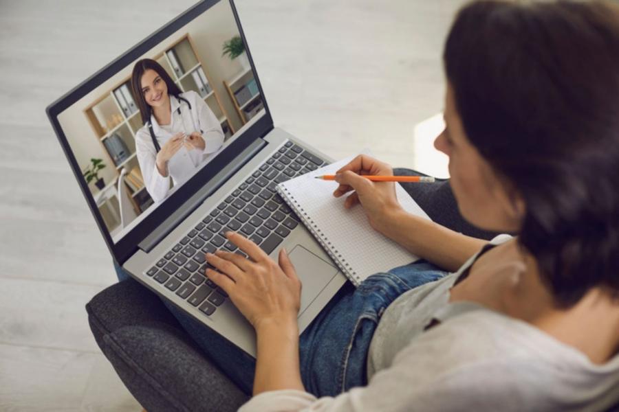 A student participating in a virtual meeting with a laptop in front of her.