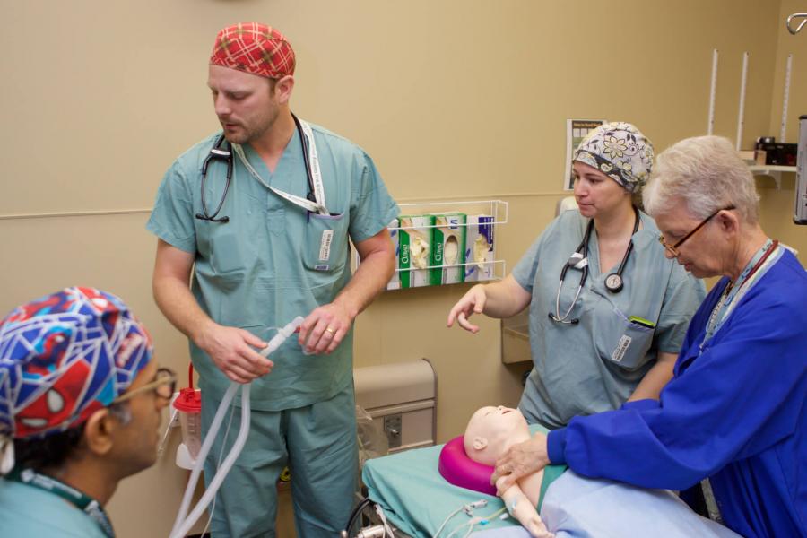 Doctors and students work with a medical mannequin during an anesthesia simulation.