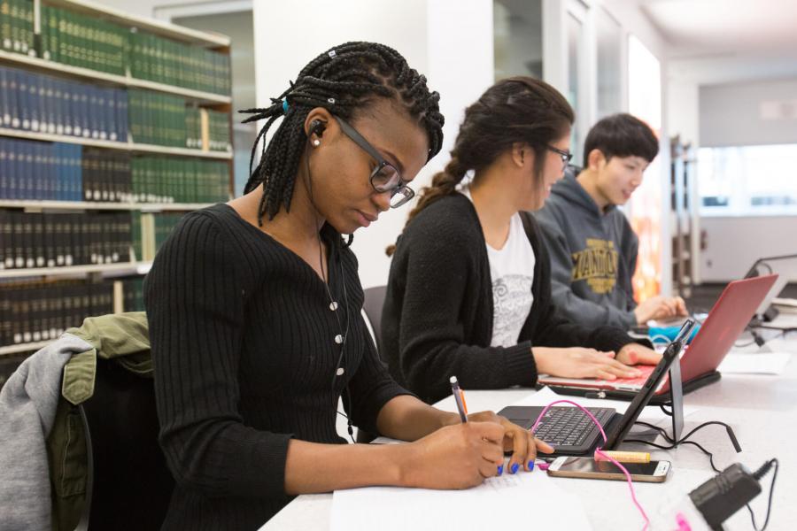 Four students seated in a row in a library.