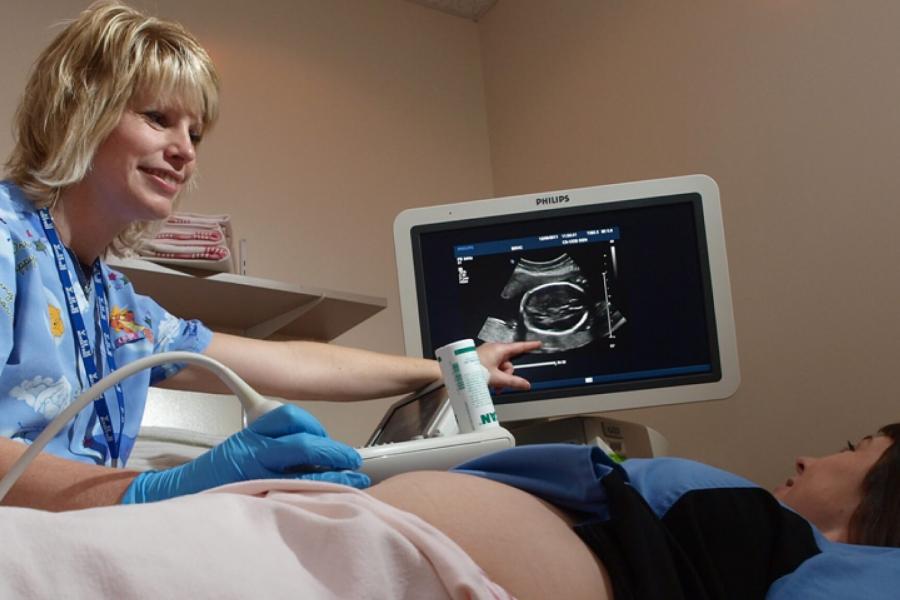 A woman points to a monitor during an ultrasound.