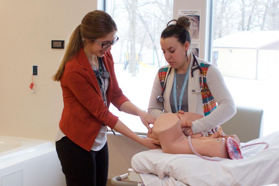 A student practices the birthing process using a simulation mannequin.