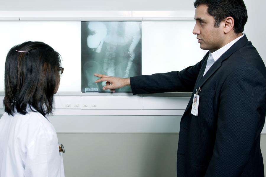 Two people reviewing an xray mounted on a light board.