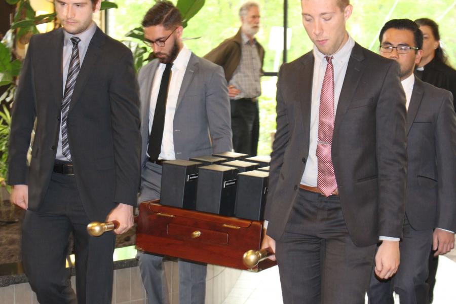 Students carry urns at a memorial service