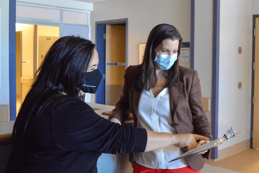 Two faculty members of the internal medicine department look at a clipboard together.
