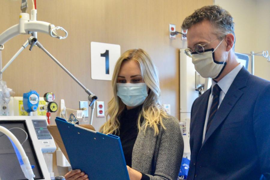 Two medical professionals look at a clipboard.