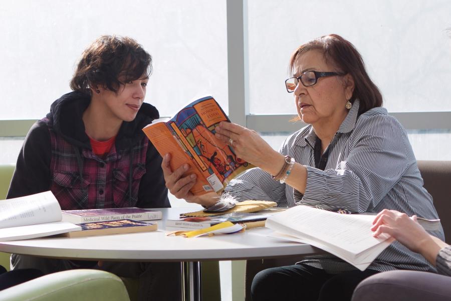 Elder sitting with a student looking at a book
