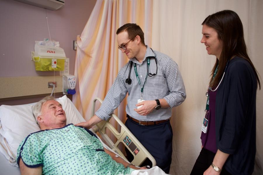 Physician stands next to a patient's bedside.
