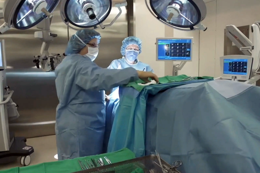 two doctors stand over a patient on the operating table.