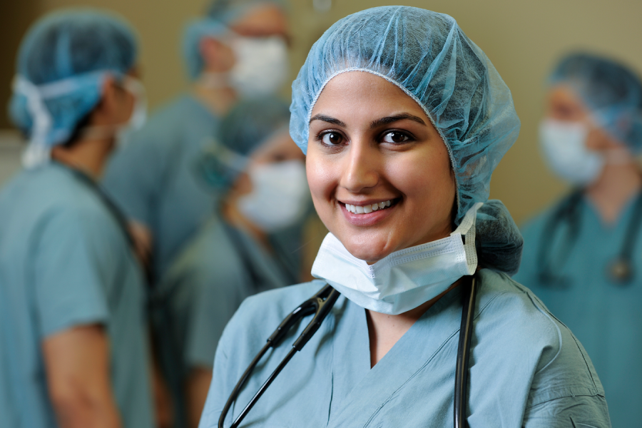 A healthcare worker in scrubs smiling.