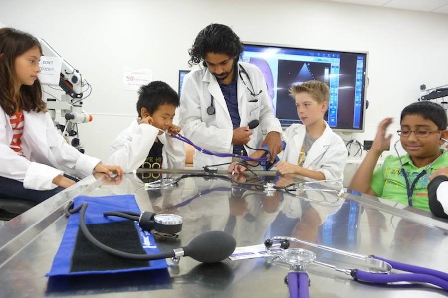 Four kids in the summer program listening to heartbeats through a stethoscope.