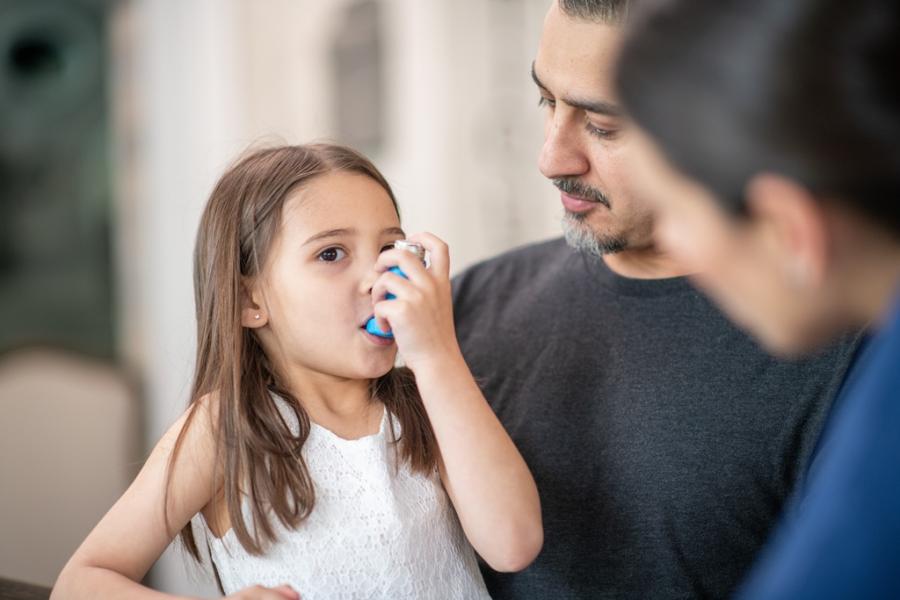 Little girl uses an asthma inhaler.