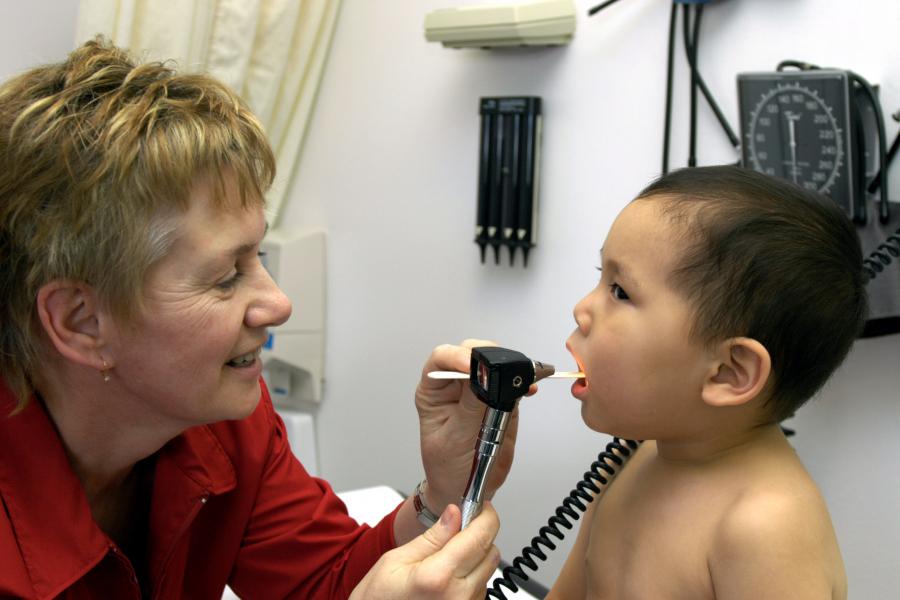 doctor examines tonsils of a young child.