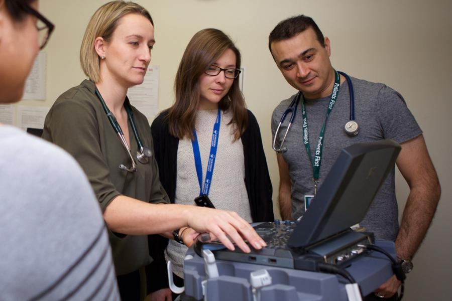 A group people looking at an ultrasound monitor.