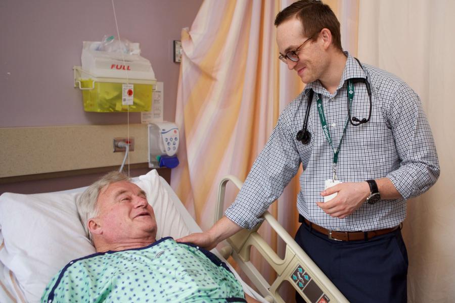 Physician comforting a patient in a hospital bed.